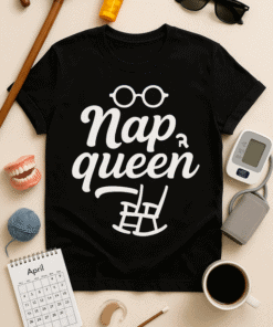 Glasses, medication, and everyday essentials around a black "Nap Queen" T-shirt on a flat lay.