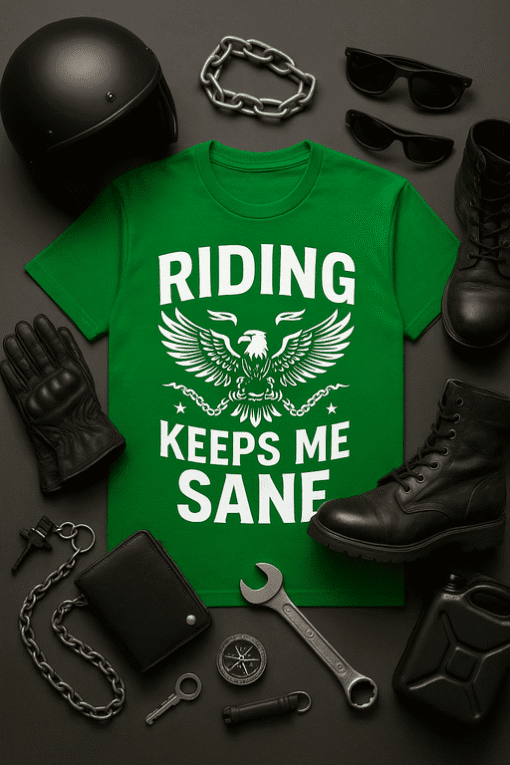 Black motorcycle helmet with visor, chain, sunglasses, gloves, boots, and wrench surrounding a green riding-themed T-shirt.