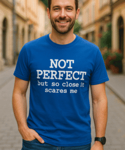 1. Smiling man wearing blue T-shirt with humorous quote, outdoor urban background.