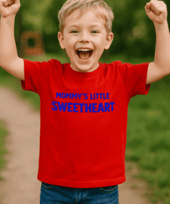Cheerful boy wearing "Mommy's Little Sweetheart" T-shirt outdoors, happy child in casual clothing.
