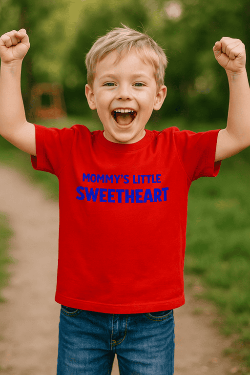 Cheerful boy wearing "Mommy's Little Sweetheart" T-shirt outdoors, happy child in casual clothing.