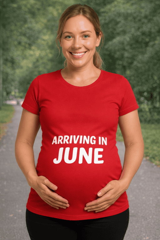 Charming pregnant woman wearing red T-shirt with "Arriving in June" text, outdoors, maternity fashion, pregnancy announcement tee, stylish pregnancy shirt.