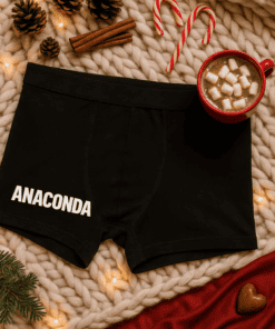 Comfy black boxer briefs with "ANACONDA" printed, cozy holiday scene with hot chocolate and candy canes.