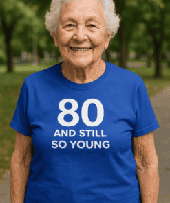 1. Happy elderly woman wearing a blue birthday T-shirt with "80 and still so young" phrase.
