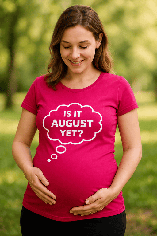 Pregnant woman wearing a pink T-shirt with "Is it August Yet?" text, outdoors.