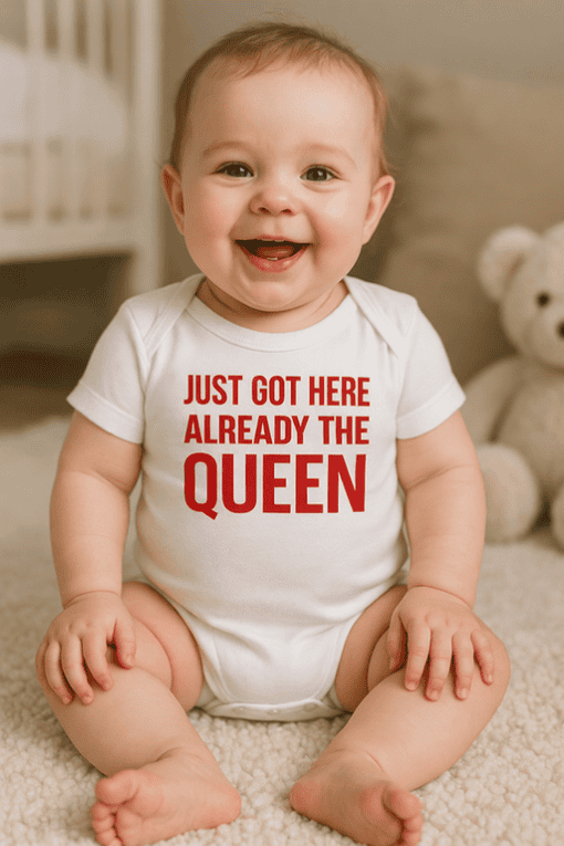 Playful baby with "Just Got Here Already The Queen" T-shirt, adorable infant attire for kids' humor, cute baby clothes.