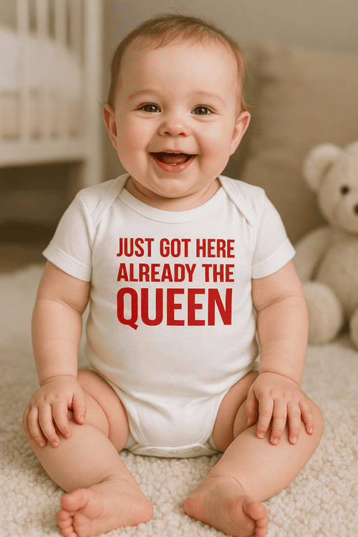 Playful baby with "Just Got Here Already The Queen" T-shirt, adorable infant attire for kids' humor, cute baby clothes.