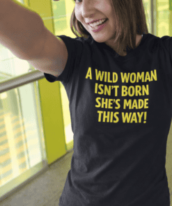 Bold woman wearing "A wild woman isn't born she's made this way" black T-shirt, smiling and taking a selfie at T-shirtplease.com.