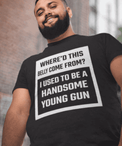 Smiling man wearing humorous handgun print t-shirt, urban background, casual fashion.