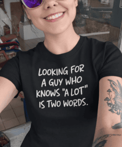 - Woman wearing black T-shirt with humorous quote, sunglasses, tattoos, bright smile.