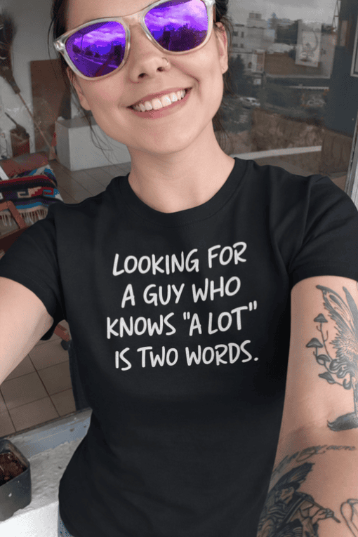 - Woman wearing black T-shirt with humorous quote, sunglasses, tattoos, bright smile.