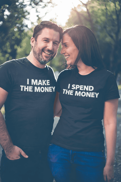 Laughing couple in black T-shirts, "I MAKE THE MONEY" and "I SPEND THE MONEY" standing outdoors, fun couple T-shirt design, matching couple shirts, humor tees.