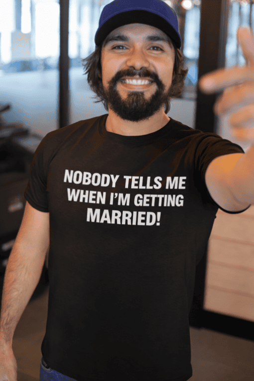 1. Smiling man wearing black T-shirt with humorous "Nobody Tells Me When I’m Getting Married" quote.