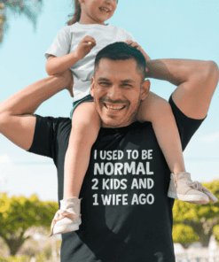 1. Smiling man with daughter on shoulders wearing humorous T-shirt outdoors.