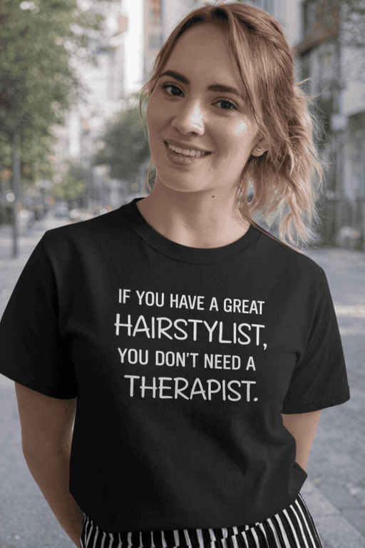 Cute woman wearing black T-shirt with humorous hairstylist quote, outdoor urban setting.