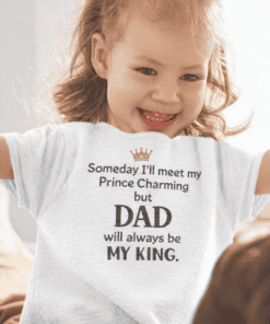 A girl wearing a T-shirt with the text "Someday I'll meet my Prince Charming but DAD will always be MY KING.".