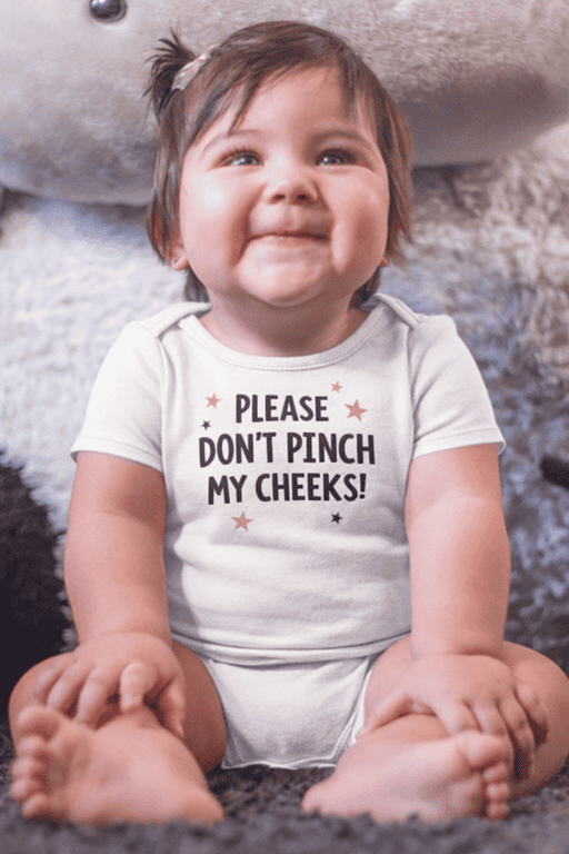 Cute baby in a funny "Please Don't Pinch My Cheeks" T-shirt, perfect for humorous infant apparel.