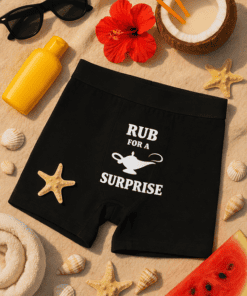Sunglasses and summer accessories with humorous boxer shorts featuring "RUB FOR A SURPRISE" quote.
